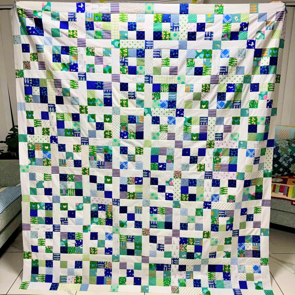 Scrappy Nine Patch Patchwork quilt with green and blue squares on a white background