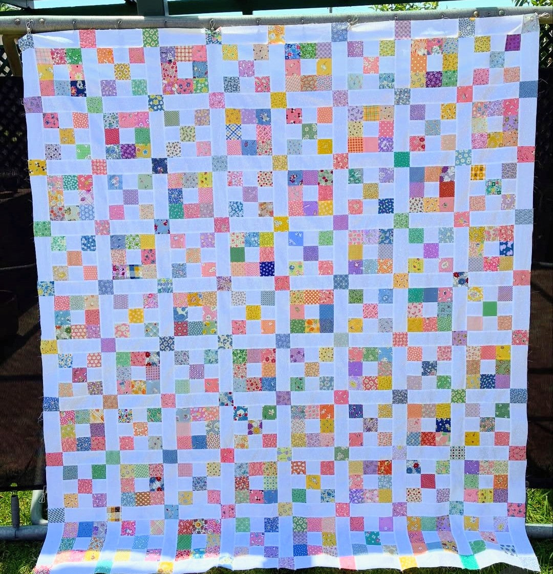 Scrappy nine patch quilt.  1930s fabrics. Colorful quilt with square patterns on a white background