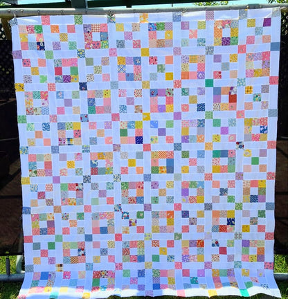 Scrappy nine patch quilt.  1930s fabrics. Colorful quilt with square patterns on a white background